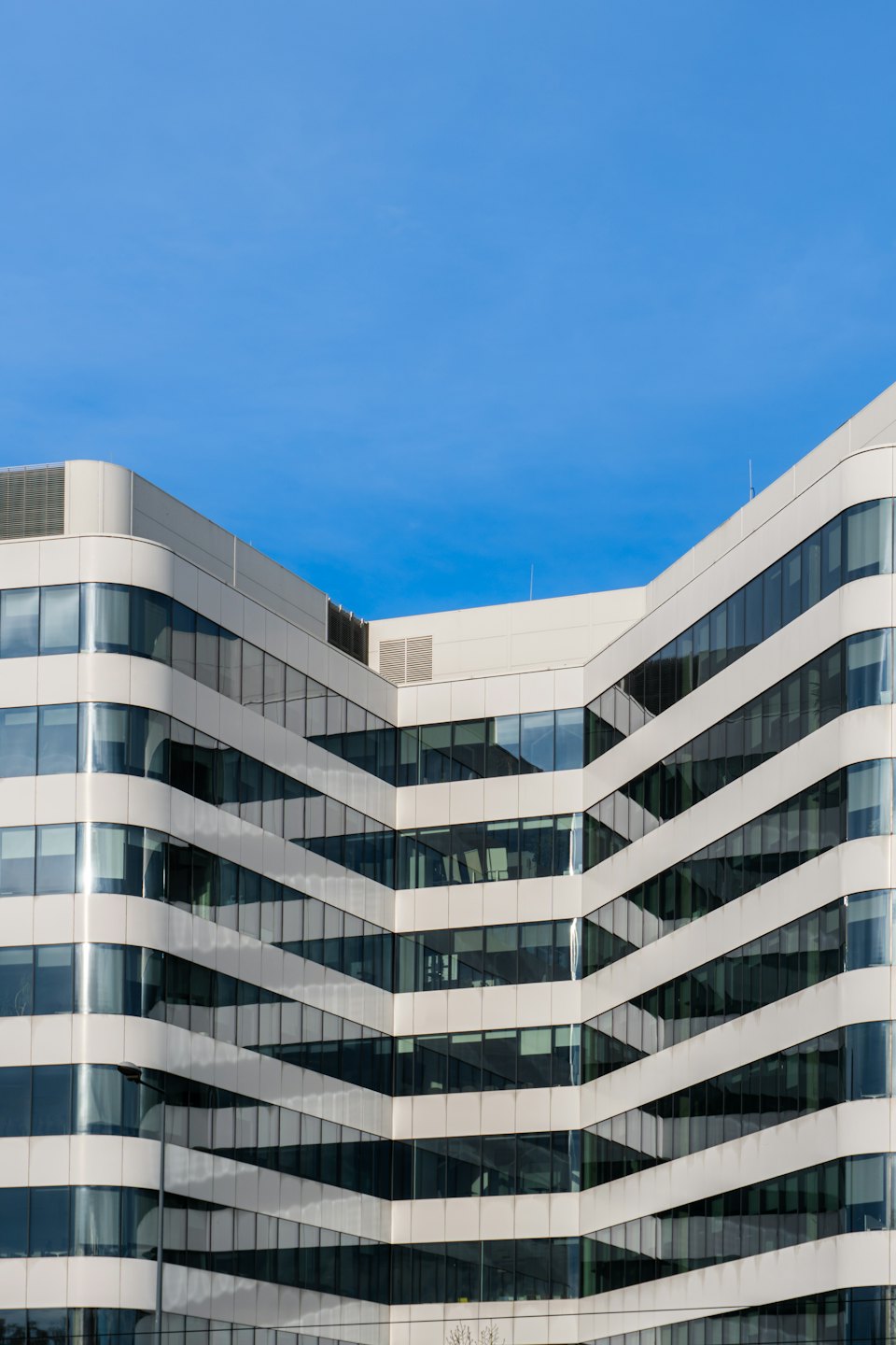 Modern office building with curved white bands and glass windows.