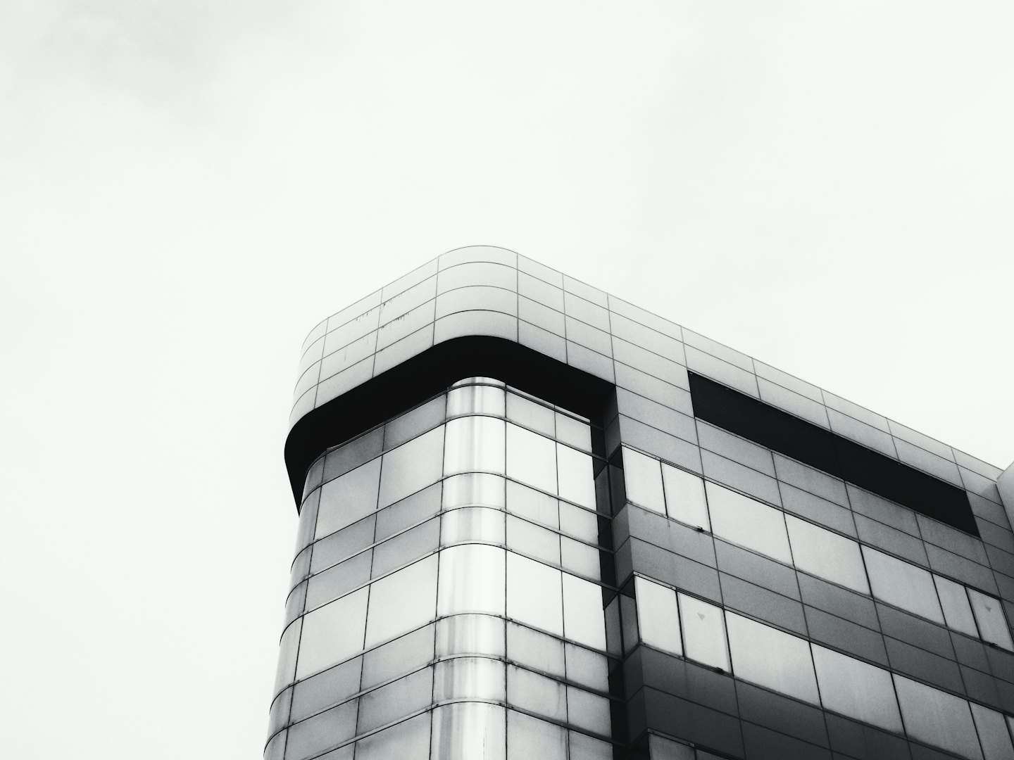 Modern commercial building with glass windows and grey panels.