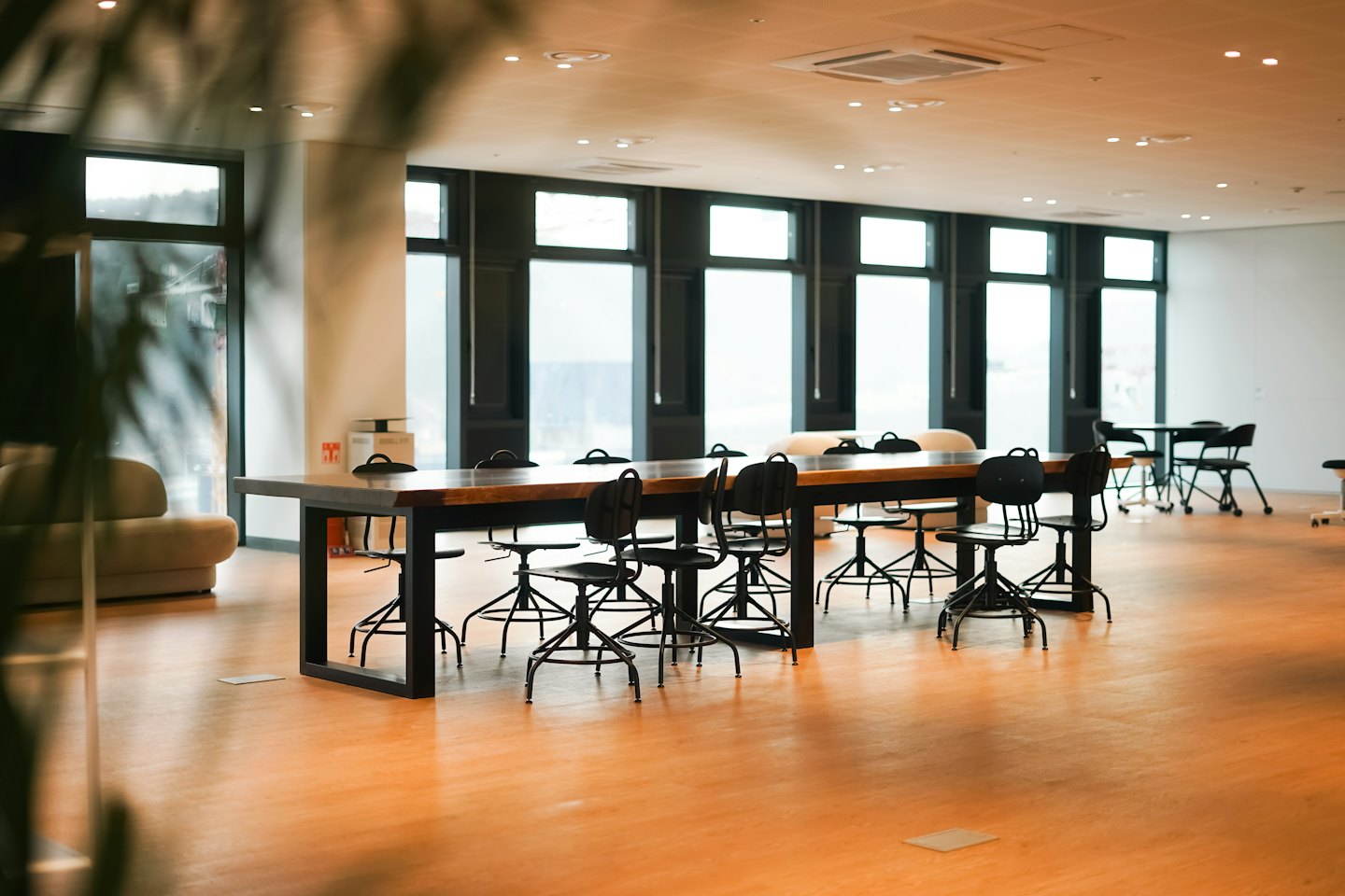 Modern open-plan office with large wooden tables and chairs.